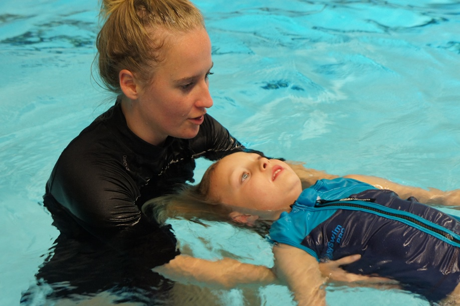 zwembadmedewerker helpt meisje zwemmen